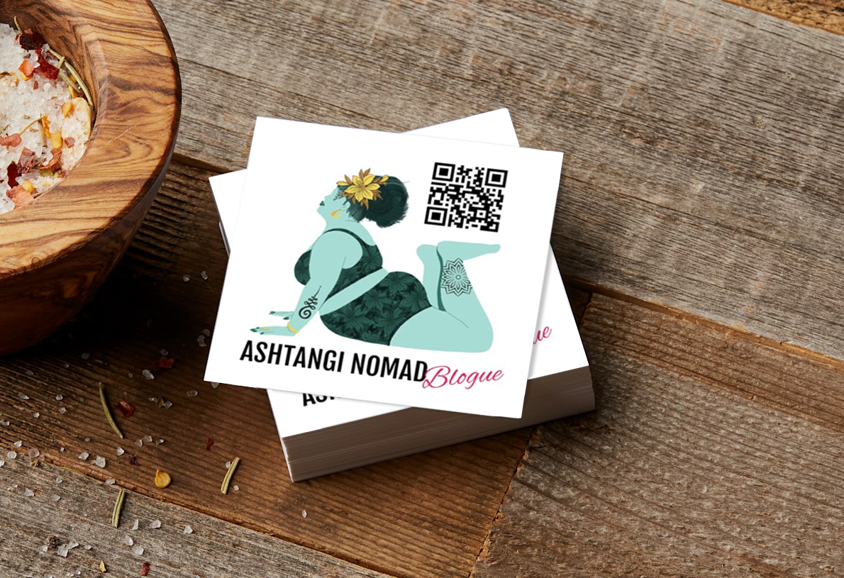 Business cards from Ashtangi Nomad laid out on a wooden table.